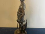 bronze statue of a boy with a dog on a blue table