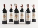 six bottles of wine are lined up in a row on a white surface