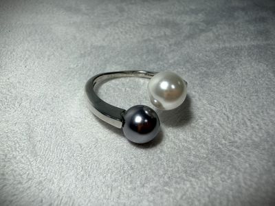 a ring with two pearls on it on a white surface