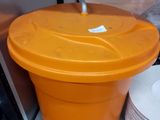 un récipient en plastique orange muni d'un couvercle, posé sur une étagère