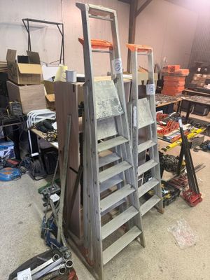 Plusieurs échelles sont empilées les unes sur les autres dans un garage.