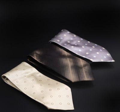 trois cravates de couleurs différentes posées les unes à côté des autres sur une surface noire