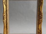 un miroir à cadre doré posé sur une table blanche