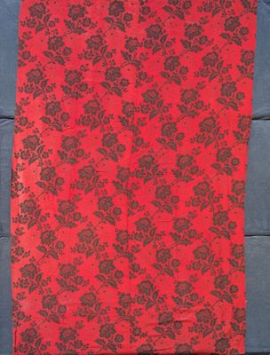 a red and black table runner with black flowers on it