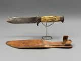 a close up of a knife with a wooden handle on a metal stand