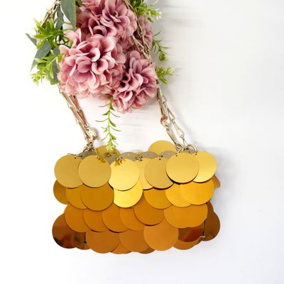 a gold purse hanging on a white wall with flowers