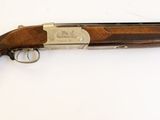 un fusil de chasse posé sur une surface blanche, muni d'une crosse en bois