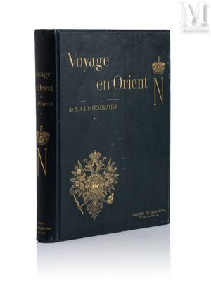 un livre noir orné d'un emblème doré, posé sur une surface blanche
