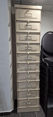 une pile de chaises dans un coin de la pièce, à côté d'une pile de classeurs