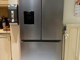 a stainless steel refrigerator in a kitchen with white tiles on the floor