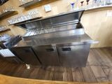 a stainless steel counter in a restaurant with wine glasses on the shelves
