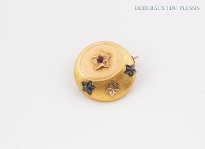 yellow gold plated brooch with black and white stars on it