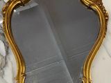 un miroir au cadre doré ouvragé posé sur un plan de travail en marbre