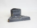 a small black object on a white surface with a white background