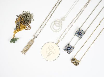 de nombreux colliers et une pièce de monnaie posés sur une surface blanche