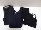 two pairs of black pants and a black sweater on a white table
