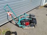 a small lawn mower sitting on the ground next to a garage