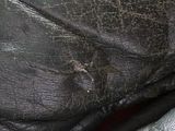 a close up of a black leather bag with a hole in it