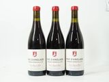 trois bouteilles de vin rouge posées l'une à côté de l'autre sur une surface blanche