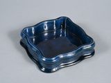un petit plat carré bleu posé sur une table blanche