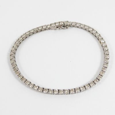 a close up of a diamond bracelet on a white surface