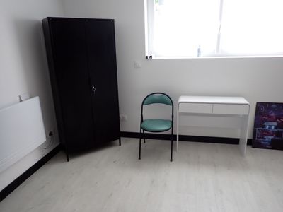 un bureau blanc et une armoire noire dans un coin de la pièce