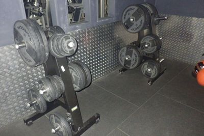 une photo d'une salle de sport avec un râtelier d'haltères
