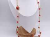 necklace with red coral beads on a wooden stand on a white background