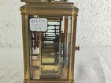 a small brass clock with a sign on the front of it