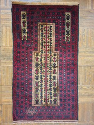 un tapis rouge et noir accroché au mur, à côté d'un parquet