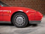 an image of a red sports car parked in front of a brick wall