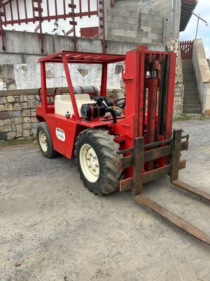 a red fork lift truck parked in front of a building