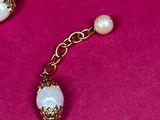 an image of a gold chain bracelet with pearls and a tassel