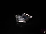 un gros plan d'un diamant posé sur une surface noire, avec un fond noir