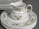 many plates and cups on the table with a pitcher on top