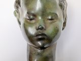 sculpture of a woman ' s head with eyes closed on a black plaque