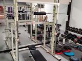 une photo d'une salle de sport avec un banc, des haltères et d'autres appareils