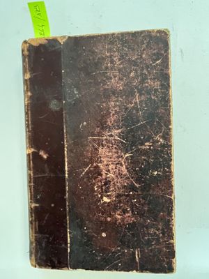 un vieux livre sur lequel est collé un autocollant vert, posé sur une table