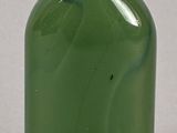 a green glass bottle with a white lid on a table