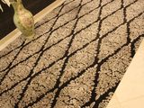 un tapis noir et blanc sur lequel est posé un vase de fleurs