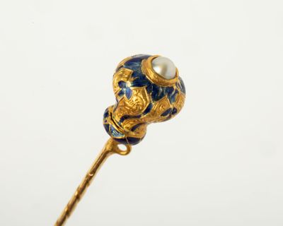 a close up of a gold stick with a blue and white flower on it
