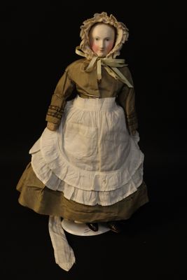 an old fashioned doll of a woman in a dress and bonnet on a black background