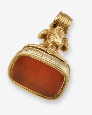 un gros plan d'un pendentif en or et en cornaline sur fond blanc