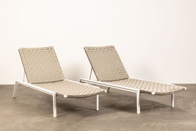 une paire de chaises longues aux assises tressées, posées au milieu d'un sol en béton