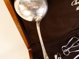 une cuillère en argent et des ciseaux dans un étui posé sur une table