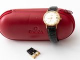 a red case with a watch on it next to a pair of scissors
