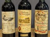 three bottles of wine are lined up on a wooden table