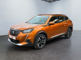 Le SUV orange est garé dans une grande pièce au sol noir.