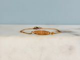 un bracelet en or orné d'un poisson, posé sur une surface en marbre