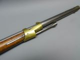 a rifle with a wooden handle and brass plated handle